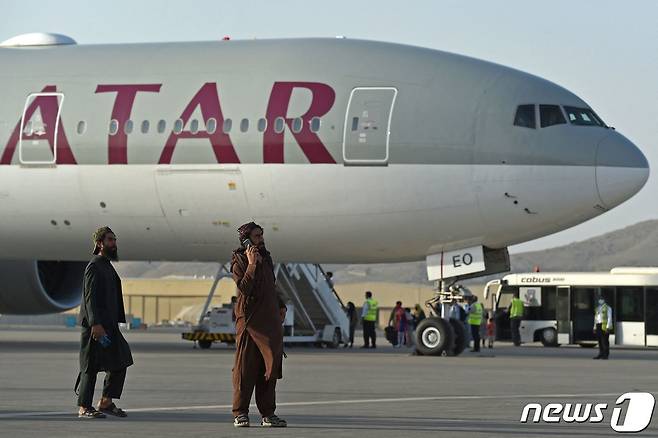 미국인 등 승객 200명이 9일(현지시간) 아프가니스탄 카불 공항에서 카타르 항공기에 오르는 동안 탈레반 조직원들이 경비를 서고 있다. 지난달 30일 밤 11시59분 마지막 미 군 수송기가 떠난 이후 첫 탈출 비행이다. © AFP=뉴스1 © News1 안은나 기자