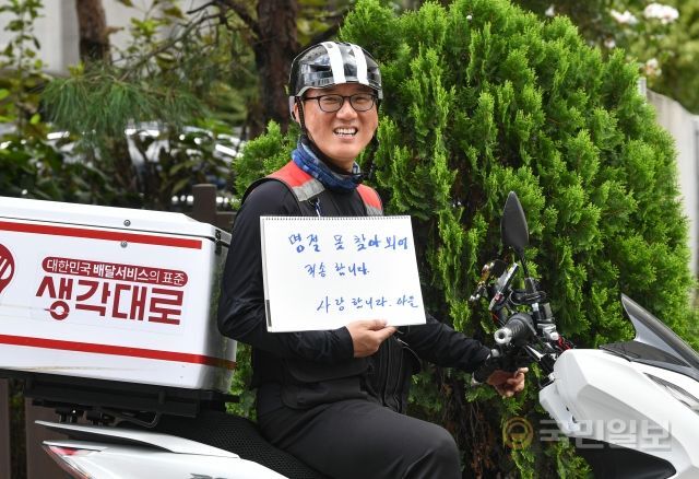 신홍철 생각대로 동대문지부 총괄본부장이 지난 8일 서울 동대문구에 위치한 사무실 앞에서 부모님에게 보내는 메시지를 든 채 활짝 웃고 있다.