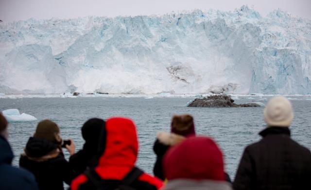 그린란드를 여행중인 관광객들이 15일 북쪽지역의 거대한 빙하의 모습을 지켜보며 카메라에 담고 있다. 그린란드=로이터 연합뉴스