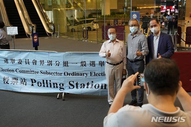 [AP/뉴시스] 홍콩 최고지도자 행정장관과 의원 반을 선출하는 권한의 선거위원회 위원 선거가 19일 실시되었다. 투표권자의 반인 4000명이 1차 투표에 참여한 투표자 3명이 기념사진을 찍고 있다