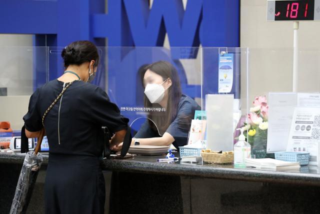 지난달 31일 오후 서울 시내 한 은행 예·적금 창구에서 한 고객이 업무를 보고 있다. 뉴시스