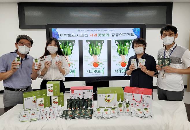 충북 충주시농업기술센터 직원과 농업회사법인 새싹나라 관계자들이 공동개발을 통해 개발한 ‘사과맛보리’ 제품을 들어보이고 있다. 충주시 제공.