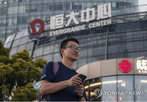 지난 21일 한 남성이 중국 상하이의 헝다센터 앞을 지나고 있다. <상하이=EPA 연합뉴스>