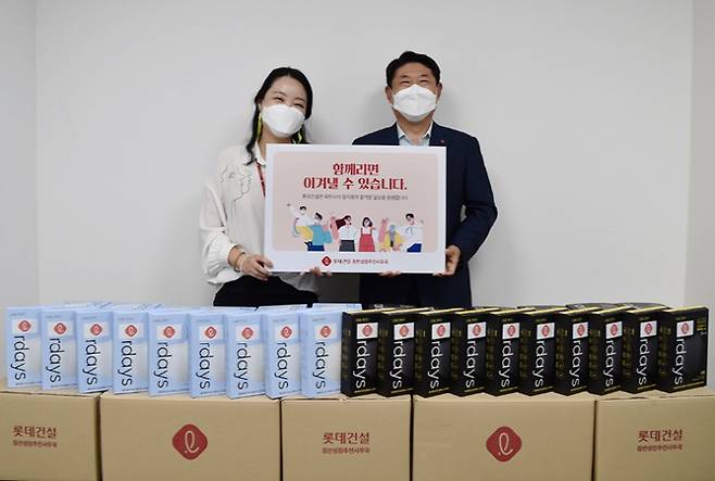 박은병 외주구매본부장(오른쪽)이 협력사를 위해 준비한 마스크 앞에서 기념사진을 찍고 있다. [사진 = 롯데건설]