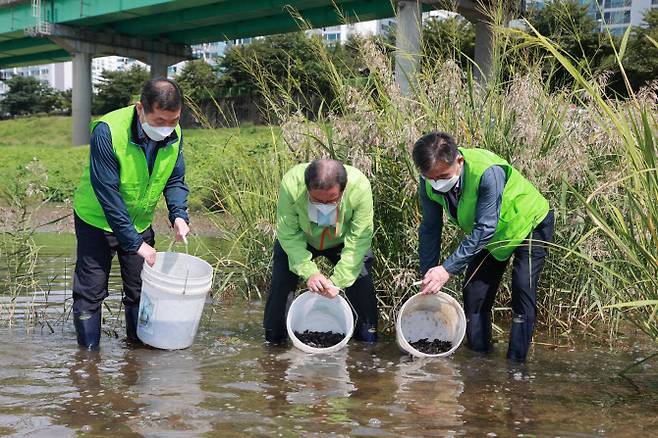 조광한 시장(가운데)과 주민들이 대농갱이 치어를 방류하고 있다.(사진=남양주시 제공)