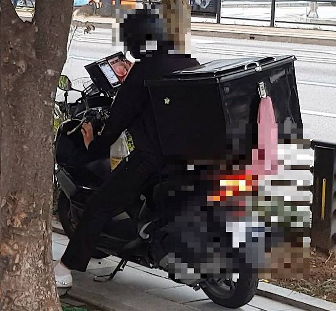 지난 22일 서울시에 위치한 빌딩 앞에서 배달원이 2개의 스마트폰을 조작하고 있다. /최정석 기자