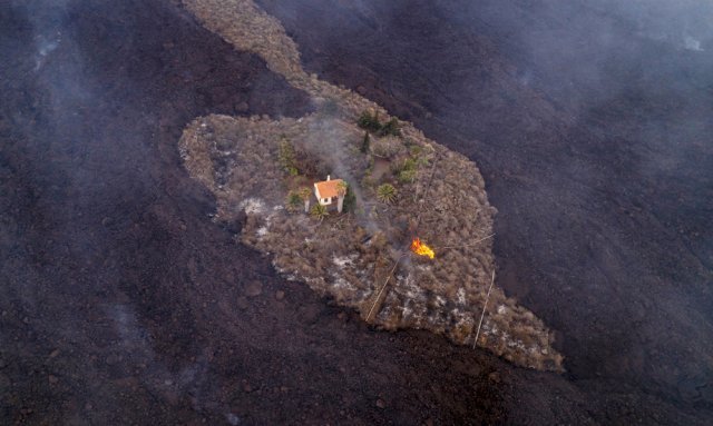 20일 스페인 카나리아스의 라 팔마 섬 라스 만차스 근처에서 화산이 폭발한 후 흘러내린 용암이 가옥들을 삼키고 있다. AP=뉴시스