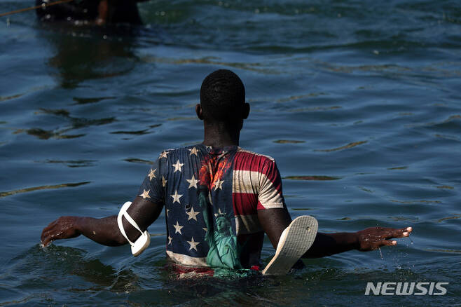 [멕시코=AP/뉴시스] 지난 20일(현지시간) 한 아이티 이주민이 미국으로부터의 추방을 피하기 위해 텍사스 델 리오에서 리오그란데 강을 건너 멕시코 시우다드아쿠나로 돌아오고 있다. 2021.09.24.