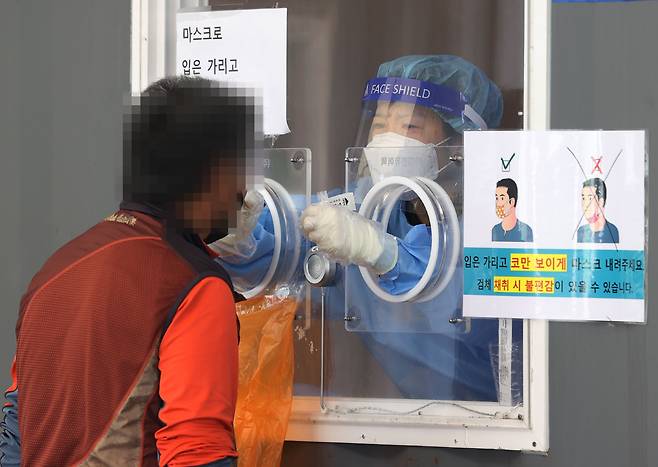 추석 연휴가 끝나고 코로나 확진자가 폭증하면서, 24일 하루 확진자 규모가 3000명을 처음 넘어섰다. 25일 오전 서울역 광장에 마련된 중구임시선별검사소에서 의료진이 검체를 채취하고 있다. /연합뉴스