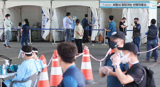지난 24일 서울 송파구 가락시장에 마련된 선별진료소에서 시민들이 코로나 19 검사를 위해 줄지어 서있다. /연합뉴스