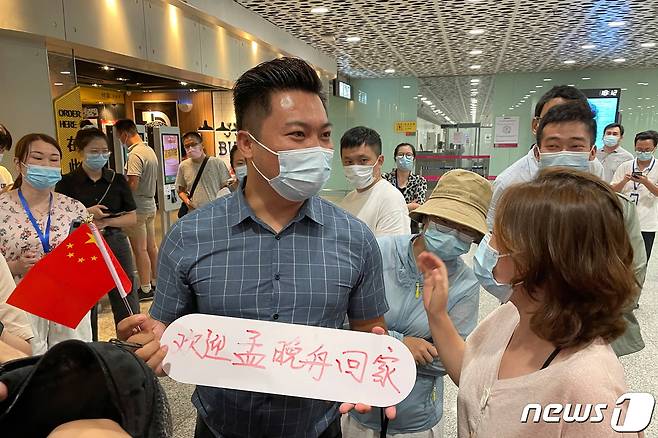 25일 선전 바오안 공항에서 한 시민이 '멍완저우의 귀국을 환영한다'는 팻말을 들고 있다. © 로이터=뉴스1 © News1 박형기