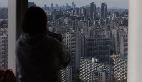 한 시민이 서울 송파구에 위치한 롯데월드타워에서 잠실주공5단지 아파트를 비롯한 주변 지역을 살펴보고 있다. <연합뉴스>