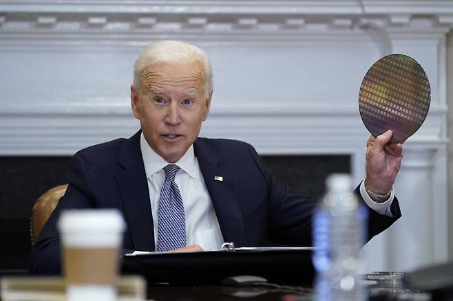 조 바이든 미국 대통령이 4월 워싱턴 백악관에서 열린 1차 반도체 화상회의에서 반도체 웨이퍼를 들어 보이고 있다.