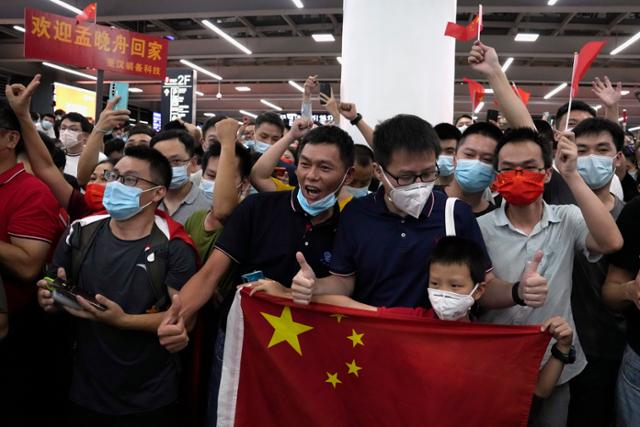 25일 중국 광둥성 선전시 바오안 국제공항에서 시민들이 오성홍기를 흔들며 멍완저우 화웨이 부회장의 귀국을 환영하고 있다. 선전=AP 연합뉴스
