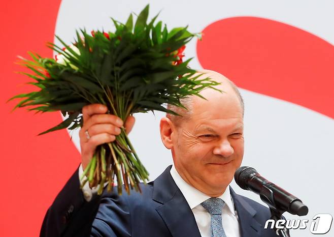올라프 숄츠 독일 사회민주당(SPD) 총리 후보가 27일 당을 상징하는 붉은색 꽃을 들어보이며 총선 승리를 기뻐하고 있다. © 로이터=뉴스1