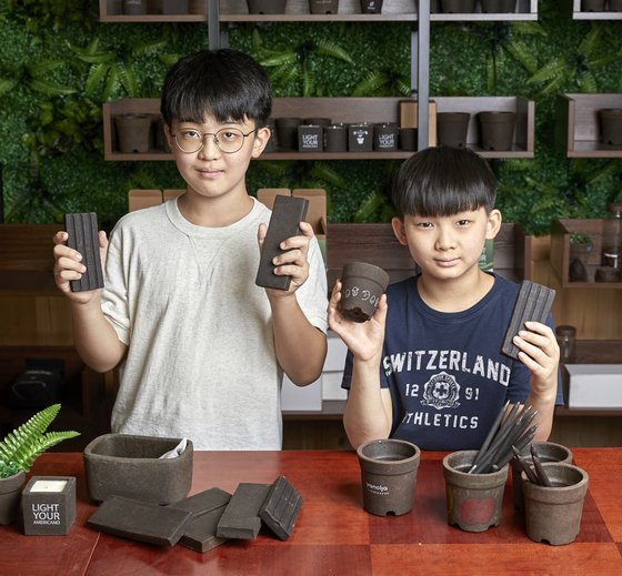 김재신(왼쪽) 학생기자·김휘윤 학생모델이 벽돌·화분·연필 등 커피박으로 만든 다양한 제품을 들어 보였다.