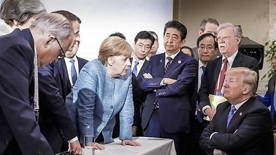 메르켈의 정치적 위상과 단호함을 보여주는 사진. 2018년 캐나다에서 열린 G7 정상회의 때 팔짱 낀 트럼프 전 대통령과 탁자 누른 메르켈 독일 총리. G7 정상들이 메르켈 좌우에서 지켜보고 있다. [연합뉴스]