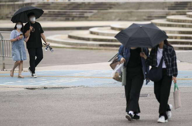 지난 27일 오후 서울 서초구 반포한강시민공원에서 갑자기 내린 비에 시민들이 우산을 쓰고 발걸음을 옮기고 있다. /뉴시스
