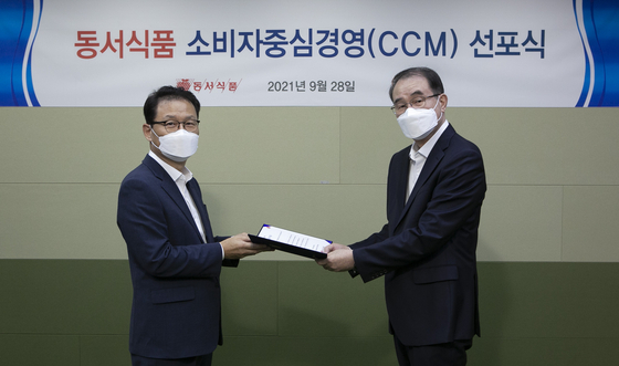 Lee Kwang-bok, Dongsuh Foods president, right, awards a certificate of appointment of the chief customer officer role to Park Young-soon, Dongsuh Foods associate vice president, at a proclamation ceremony held by Dongsuh Foods at its Seoul office in Mapo District, western Seoul, on Tuesday.