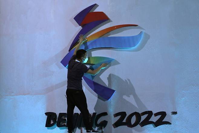 한 남성이 지난 17일(현지시각) 베이징에 있는 2022 베이징겨울올림픽 엠블럼을 정돈하고 있다. 베이징/로이터 연합뉴스