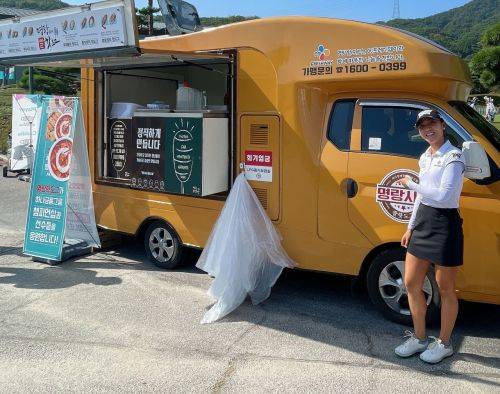 리디아 고가 핫도그 푸드트럭을 가르키며 활짝 웃고 있다. 사진제공=하나금융그룹