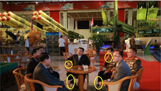 김정은 국무위원장이 11일 개막한 국방발전전람회 '자위-2021' 전시장에서 고위간부들과 담배를 피고 있다. 김 위원장 왼쪽 뒤 초대형 방사포가 전시돼 있다. [조선중앙통신 홈페이지 캡처]