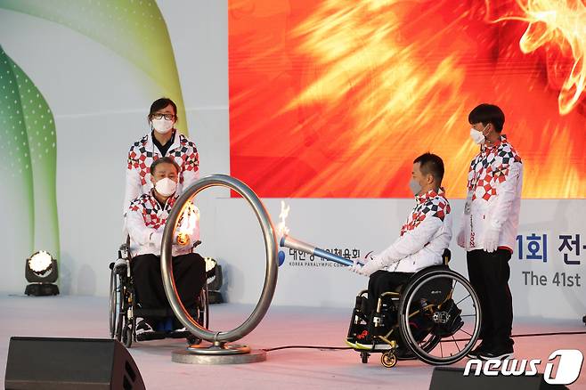 (왼쪽부터) 한국교통장애인협회 김락환 중앙회장, 육상 유병훈 선수가 제41회 전국장애인체육대회 성화를 점화하고 있다. (대한장애인체육회 제공) © 뉴스1