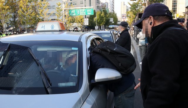 민노총 노조원이 유리창을 넘어 지나가던 택시의 핸들을 낚아채고 있다
