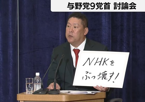 18일 열린 일본 중의원 선거 9개 당대표 토론회에서 다치바나 다카시 'NHK당' 당수가 ″NHK를 쳐부수자″는 당론을 적은 종이를 들고 있다. [유튜브 화면 캡처]