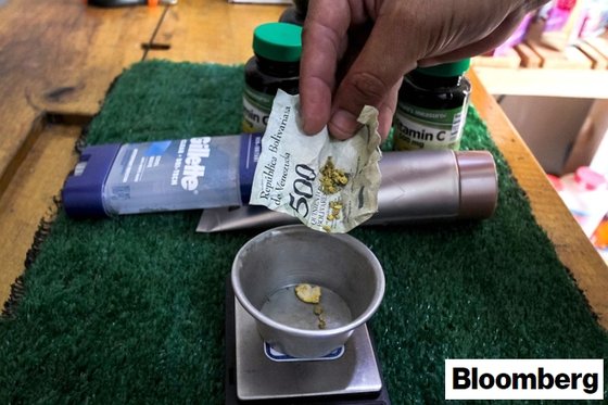 베네수엘라 투메레모의 한 약국에서 손님이 결제를 하기 위해 '볼리바르' 지폐에 싸여있던 금을 내고 있다. [블룸버그통신 캡처]