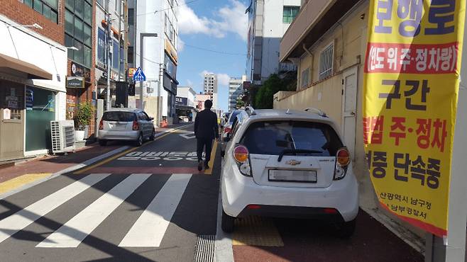울산 남구 보행환경개선지구에서 한 시민이 지난 20일 인도에 세워둔 차량을 피해 차도로 걸어가고 있다.