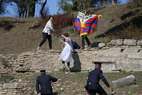 지난 19일 그리스 아테네 성화 점등식에서 티베트 인권운동가 3명이 티베트 국기와 ‘대학살 금지’라고 적힌 현수막을 흔들다 경찰에 체포됐다. [AP=연합]