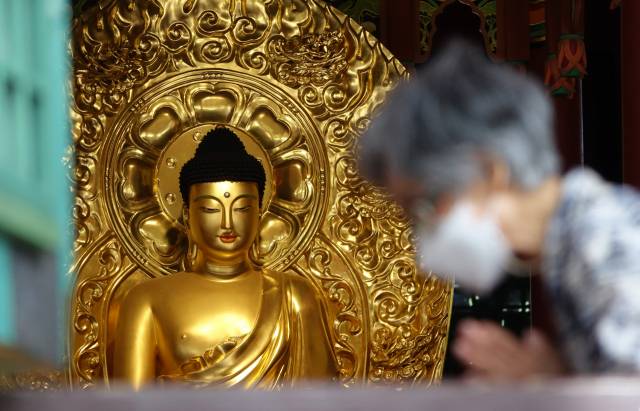 서울 종로구 조계사를 찾은 신도가 불상 앞에서 합장하고 있다./연합뉴스