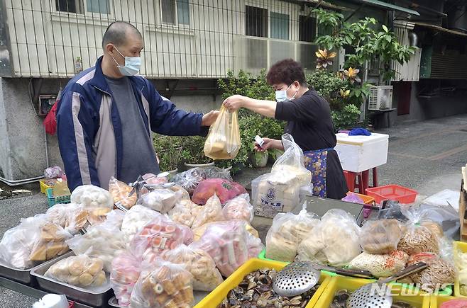 [타이베이=AP/뉴시스] 대만 수도 타이베이에서 19일 코로나19 예방을 위해 마스크를 착용한 주민이 노점상을 찾아가 식료품을 사고 있다. 2021.10.21