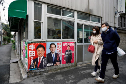 일본 중의원 선거운동이 시작된 지난 19일 한 커플이 정당 대표의 포스터가 붙은 도쿄의 길거리를 지나고 있다. 도쿄=EPA연합뉴스