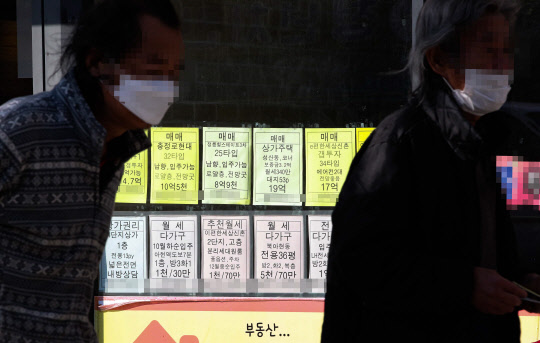 서울 서대문구의 부동산 중개업소에 게시된 매물 가격 안내판 앞을 시민들이 지나가고 있다. 연합뉴스