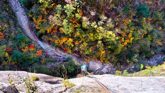 암벽을 타는 한 여성 등반가가 설악산 소토왕골 암벽에서 물감을 뿌려놓은 듯한 풍경속으로 하강하고 있다. 김상선 기자