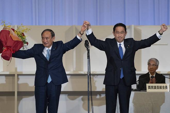 기시다 후미오 일본 총리(오른쪽)가 지난달 29일 자민당 총재 선거 당선이 확정되자 스가 요시히데 전 총리와 함께 축하하고 있다. 도쿄 | AP연합뉴스