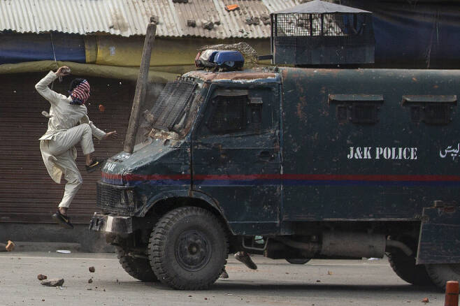 인도 북부 카슈미르의 스리나가르에서 복면을 쓴 반정부 시위자가 경찰차 위로 뛰어오르고 있다. / AP 연합뉴스