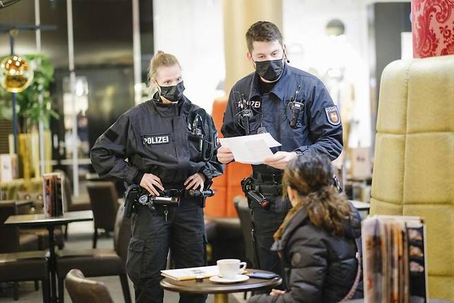 독일의 한 식당에서 경찰관들이 손님들의 예방접종 증명서를 확인하고 있다 / 사진 = AP