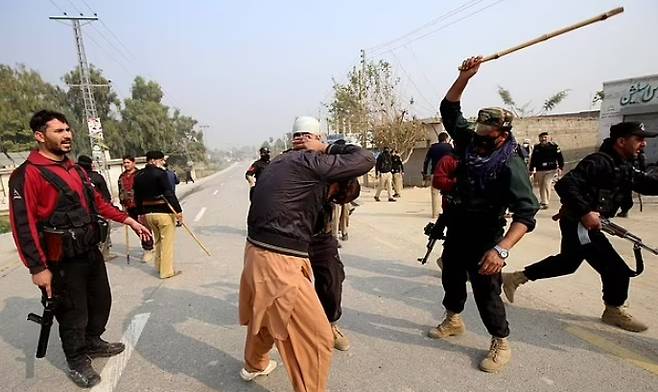파키스탄 현지시간으로 28~29일, 무슬림 약 5000명이 이슬람경전(코란)을 불태운 혐의로 체포된 피의자를 똑같이 불태워야 한다고 주장하며 경찰서를 습격했다. 사진은 폭도들을 진압하려 몽둥이를 휘두르고 있는 파키스탄 경찰과 군병력. EPA 연합뉴스