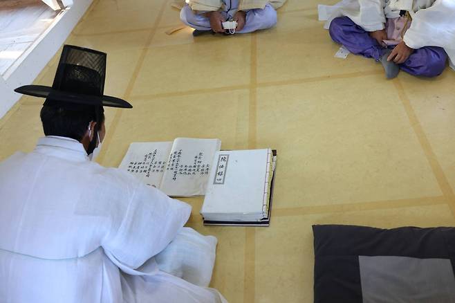 Jeong Bong-ho reads Yuwonrok, a list of students at a Confucian academy, on an ondol floor.