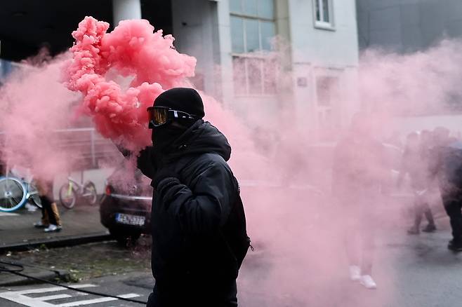 5일 벨기에 브뤼셀의 한 시위대가 붉은 화염이 발생하는 시위 도구를 들고 있다. AFP=연합뉴스