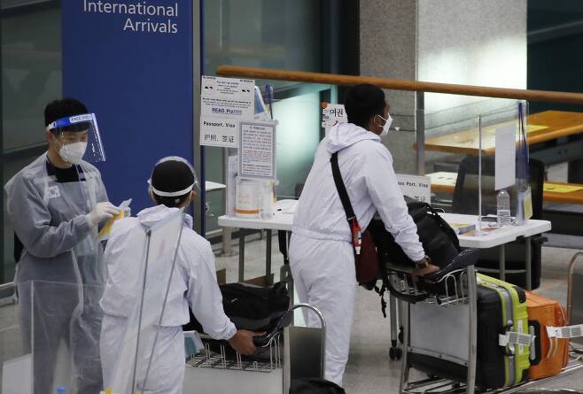6일 인천국제공항 1터미널에서 해외 입국자들이 방역요원의 안내를 받고 있다. [뉴스1]