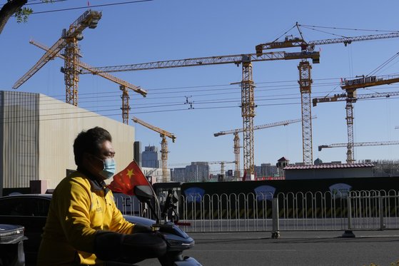 지난 10월 중국 베이징의 한 건설현장 앞을 음식배달업체 배송 기사가 지나가고 있다. [AP= 연합뉴스]