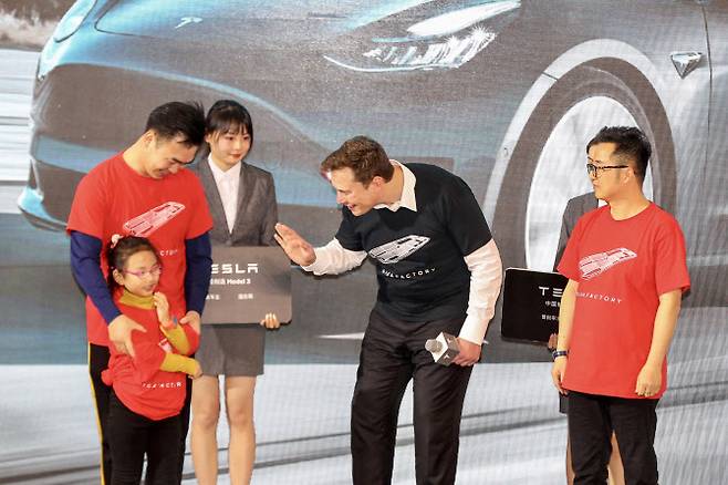 머스크 CEO가 지난 2020년 상하이 제1공장에서 만든 테슬라 모델3를 처음으로 고객에게 인도하는 행사에서 어린이에게 말을 걸고 있다. (사진= AFP)