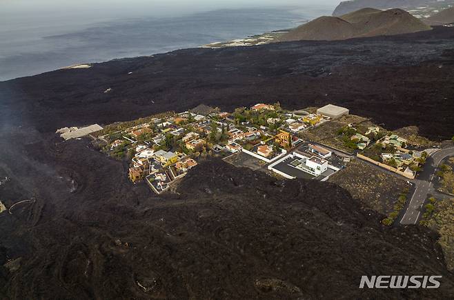 [라팔마=AP/뉴시스] 6일(현지시간) 스페인 카나리아제도 라팔마섬에서 화산 용암으로 인해 주택이 고립되어 있다. 2021.12.08.
