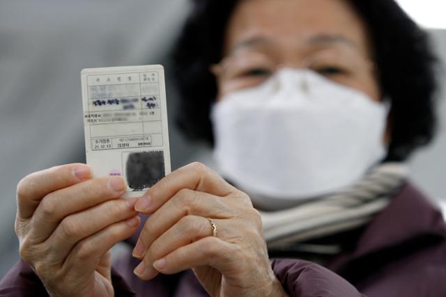 16일 서울 성동구 옥수동주민센터에서 한 주민이 코로나19 백신 접종완료 스티커를 붙인 신분증을 들어보이고 있다. 뉴스1