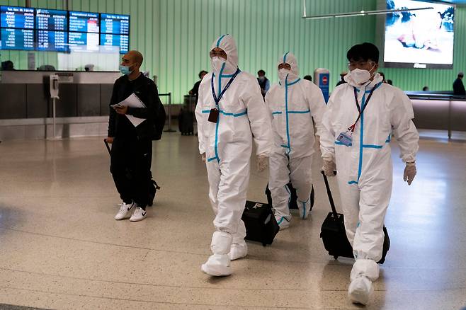 중국의 대형 국유 항공사인 에어차이나(중국국제항공) 여객기 승무원들이 지난달 30일(현지시간) 미국 로스앤젤레스(LA) 국제공항에 도착해 방호복을 입은 채 입국장을 빠져나가고 있다. 세계 각국이 신종 코로나바이러스 감염증(코로나) 새 변이 '오미크론' 확산에 비상이 걸렸다. /AP연합뉴스