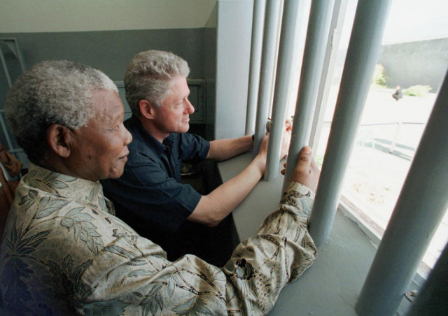 넬슨 만델라(왼쪽) 전 남아공 대통령과 빌 클린턴 전 미국 대통령이 1998년 3월 27일 남아프리카공화국 케이프타운에 있는 로벤섬을 방문해 감옥 안에서 바깥을 함께 바라보고 있다./AP연합뉴스